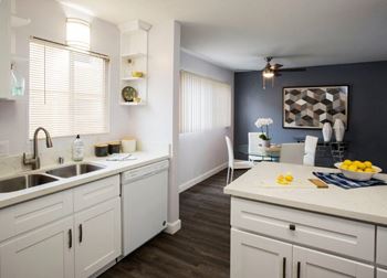 A kitchen with white cabinets and a wooden floor.